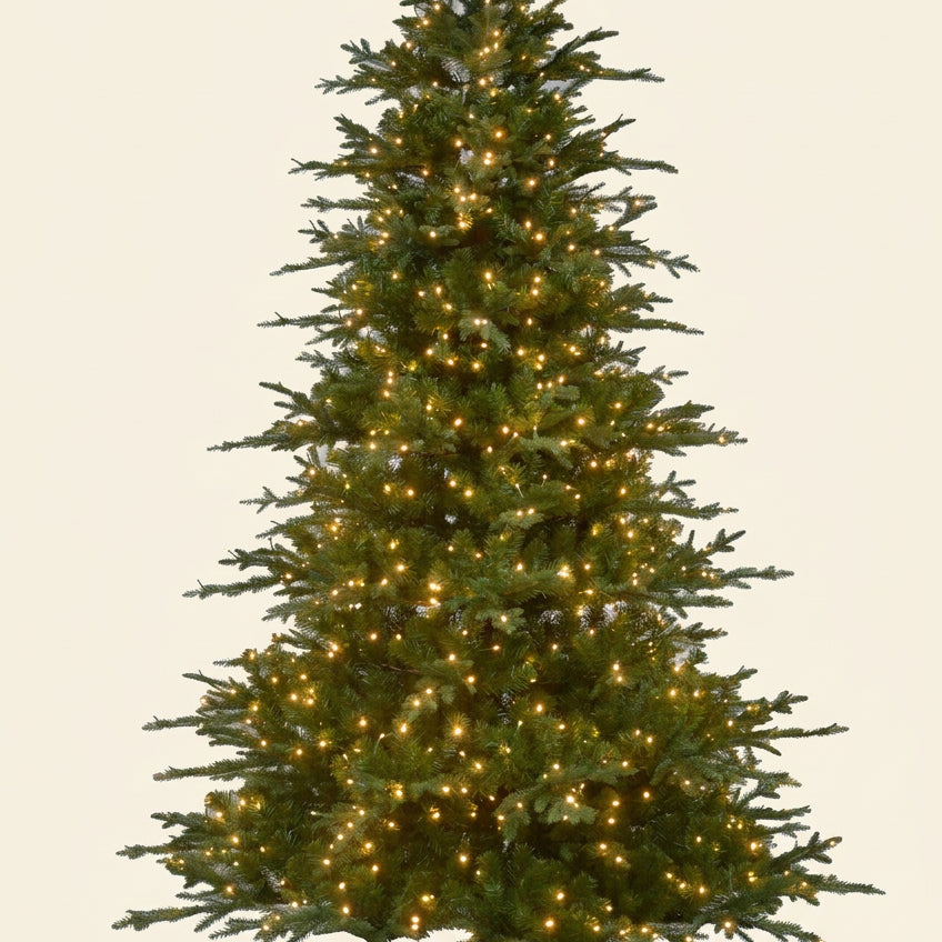 A pre-lit artificial Christmas tree with green needles and warm white lights, standing on a black metal stand against a plain white background.